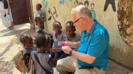 Tom shares the gospel with children of Rainy Season, using a flower as an illustration.